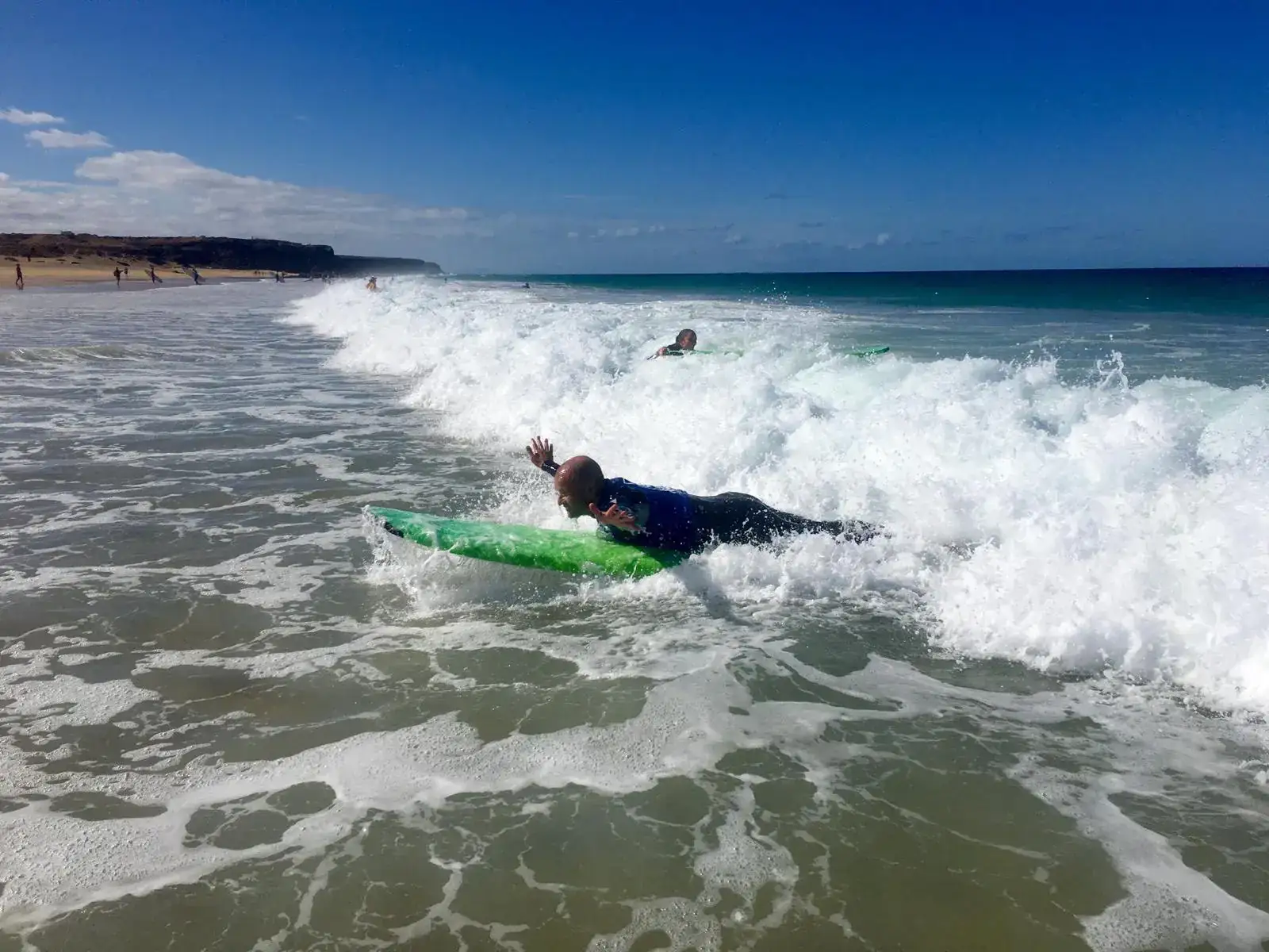 Beginner surfing a whitewater wave during a surf course in Fuerteventura