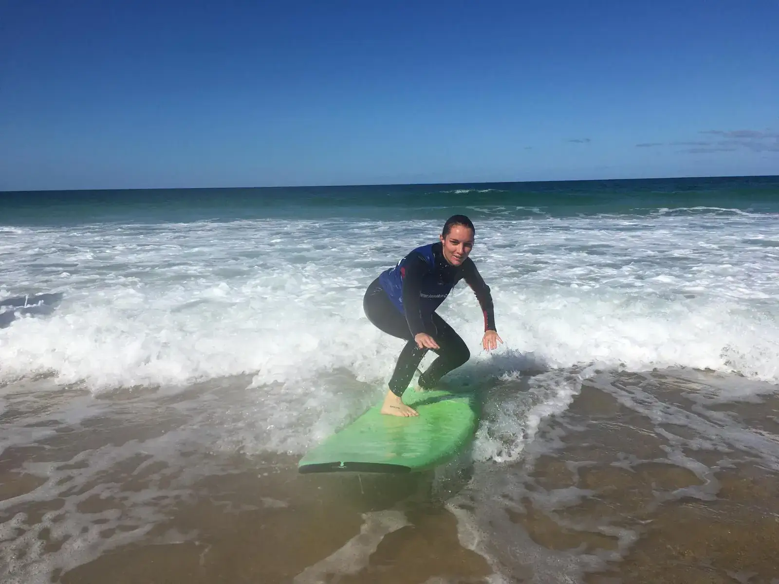 Beginner standing on their first wave during a surf course in Corralejo, Fuerteventura